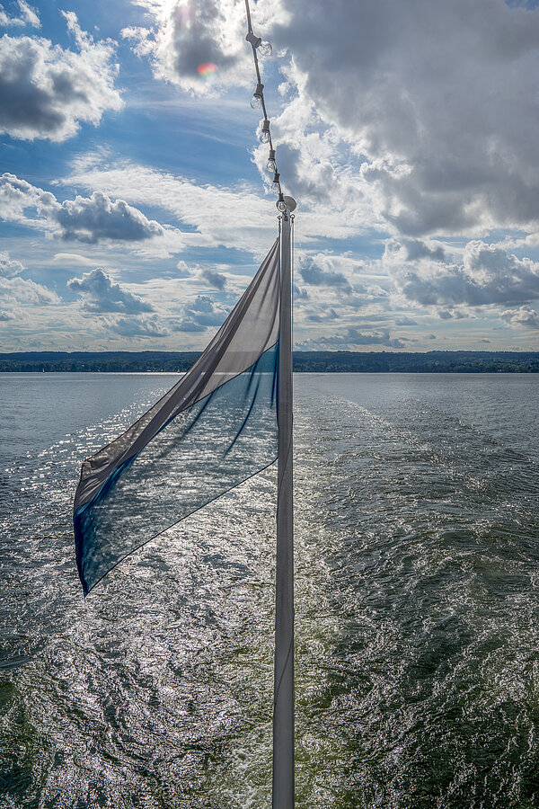 Flag from the stern with a view of Lake Ammersee