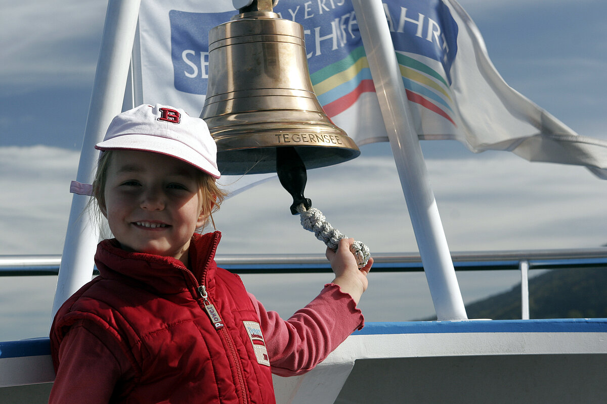 Kind an Schiffsglocke auf einem Schiff am Tegernsee