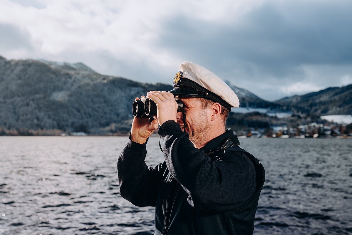 Schiffsführer mit Fernglas am Tegernsee